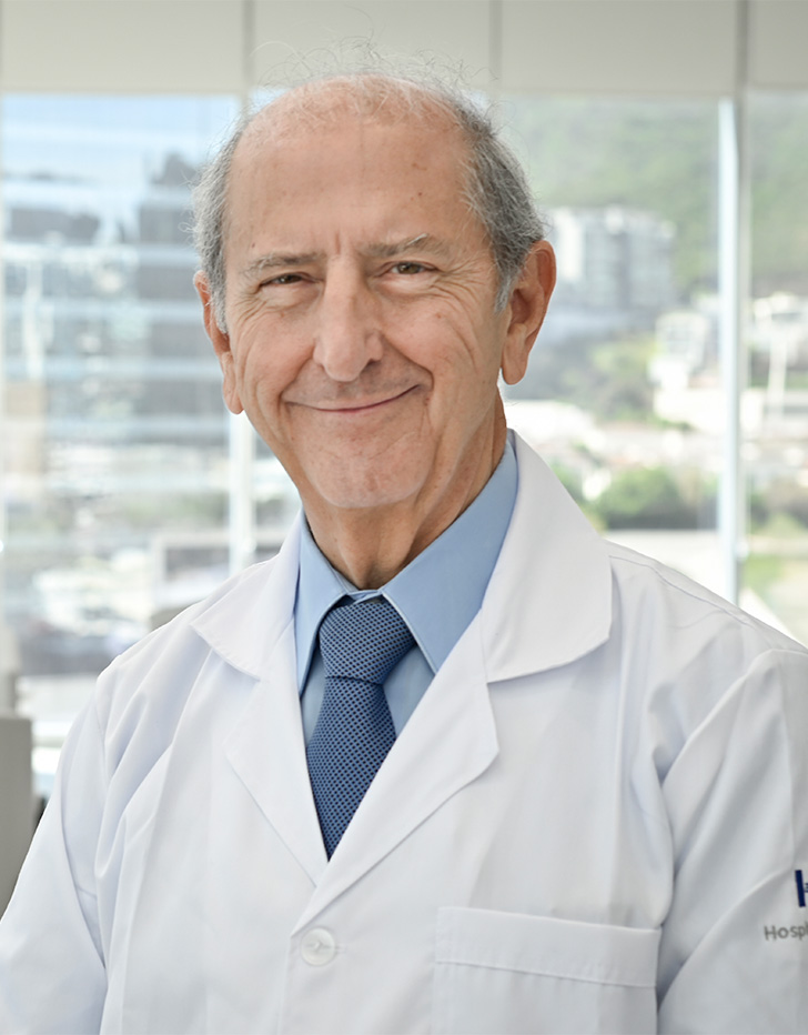 Es la foto de perfil de un ginecólogo y obstetra en San Pedro Garza de Hospital Angeles Valle Oriente. Usa una bata blanca con una camisa azul claro y una corbata azul. Está sonriendo.