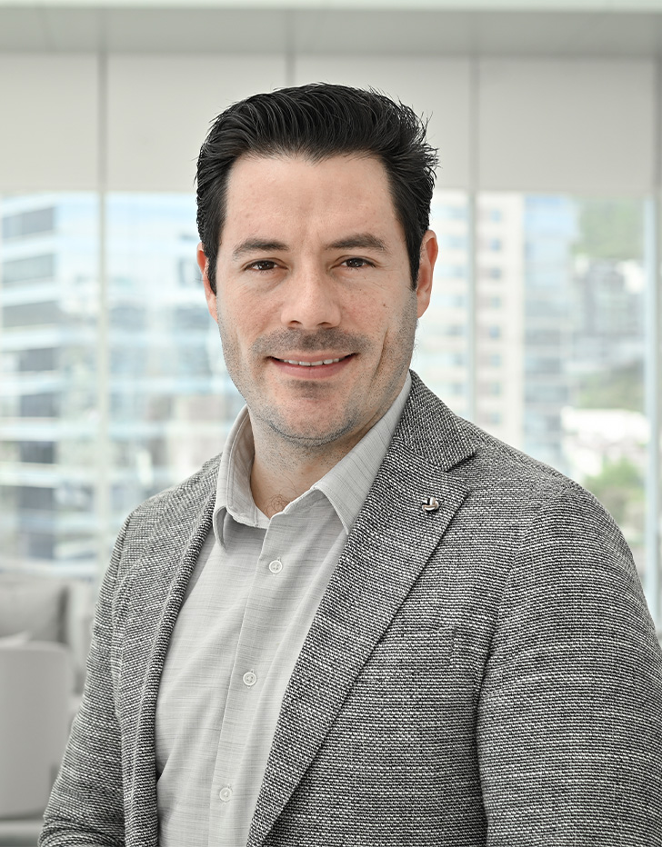 Es la foto de perfil de un cardiólogo intervencionista en San Pedro Garza de Hospital Angeles Valle Oriente. Usa un saco gris y una camisa color camel. Tiene el cabello café oscuro. Está sonriendo ligeramente.