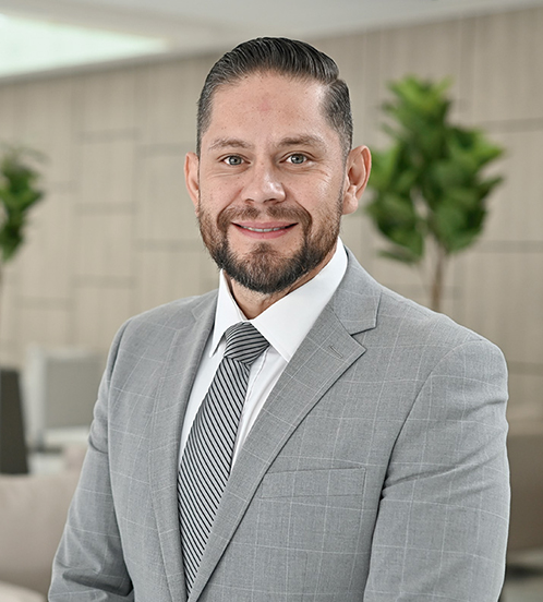 Es la foto de perfil de un cirujano general en Querétaro de Hospital Angeles Centro Sur. Viste un traje gris con cuadros blancos y camisa blanca. Usa corbata gris con lineas verticales negras.