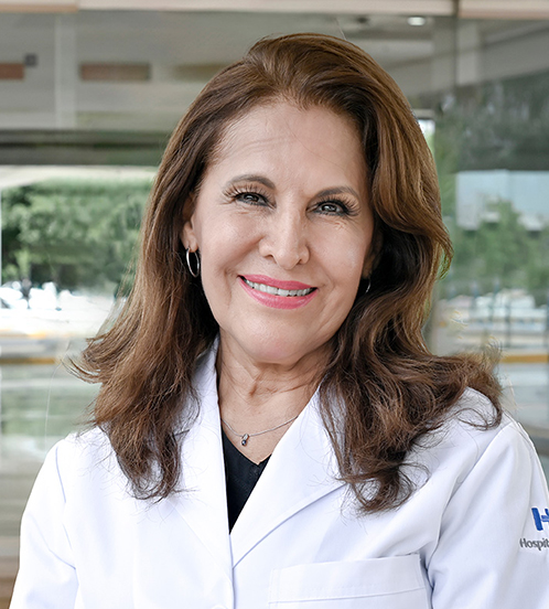 Es la foto de perfil de una ginecóloga y obstetra en Culiacán de Hospital Angeles Culiacán. Utiliza una bata blanca con una blusa azul eléctrico, tiene el cabello debajo de los hombros.