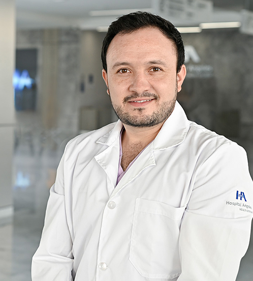 Es la foto de perfil de un urólogo en Querétaro de Hospital Angeles Centro Sur. Usa un uniforme azul marino y una cadena gruesa plateada.