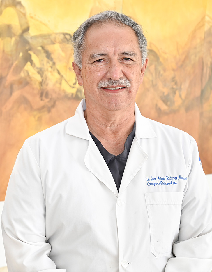 Es la foto de perfil de un ortopedista y traumatólogo en Ciudad Juárez de Hospital Angeles Ciudad Juárez. El doctor tiene el cabello y el bigote canoso, está sonriendo y utiliza una bata blanca.