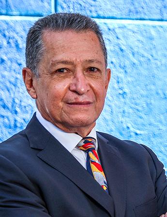 Es la foto de perfil de un cirujano neurológico en León de Hospital Angeles León. Utiliza un saco azul marino, camisa blanca y una corbata azul marino con amarillo y rojo.