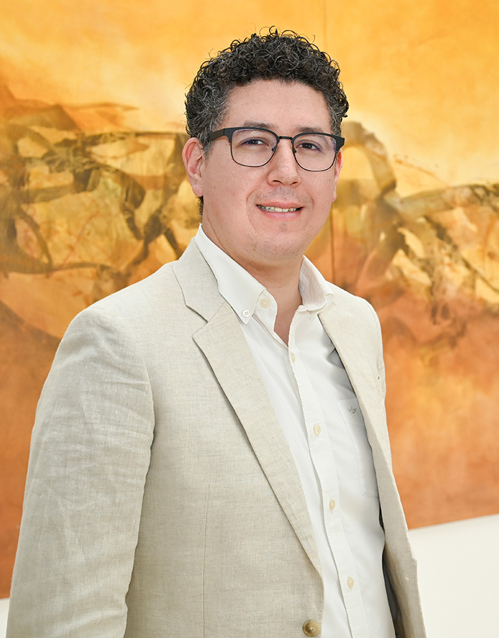 Es la foto de perfil de un pediatra especialista en neurología pediátrica en Ciudad Juárez de Hospital Angeles Ciudad Juárez. Trae puesto un traje beige y una camisa. Utiliza lentes y tiene el cabello oscuro. 