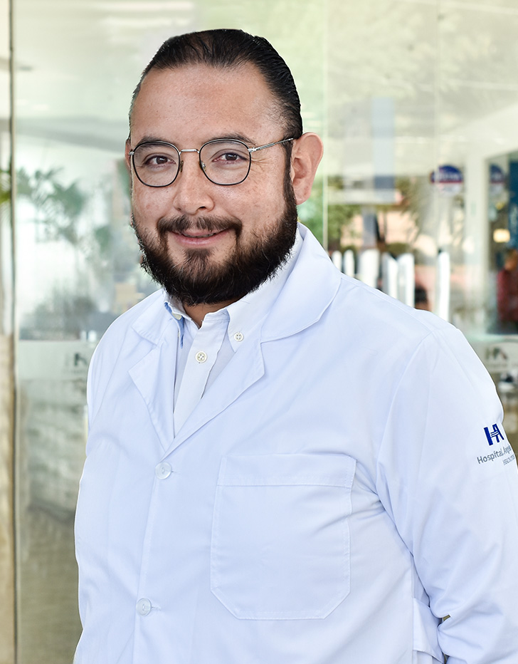 Es la foto de perfil de un otorrinolaringólogo en Ciudad de México de Hospital Angeles. El doctor viste una bata con camisa blanca a rayas rojas muy finas y una corbata negra con lunares blancos.
