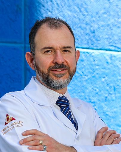 Es la foto de perfil de un cirujano neurológico en León de Hospital Angeles León. Utiliza una bata blanca, tiene camisa blanca y una camisa azul marino.