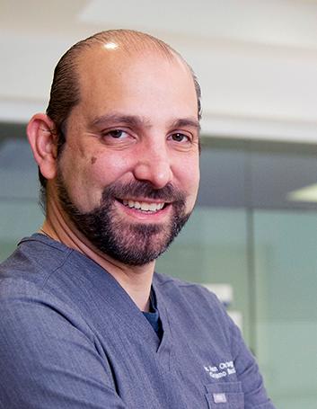 Es la foto de perfil de un cirujano general en Huixquilucan de Hospital Angeles Lomas. Usa un uniforme de color gris, tiene barba y bigote.