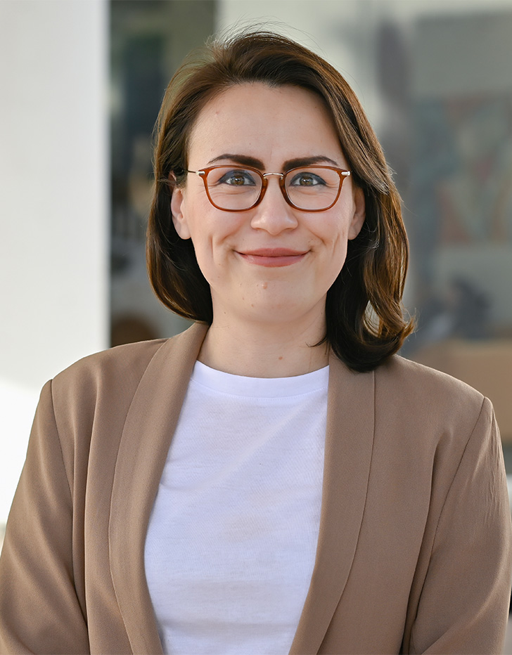 Es la foto de perfil de una ortopedista y traumatóloga en Tijuana de Hospital Angeles. Usa un blazer color café claro. Tiene el cabello corto y café. Usa lentes y está sonriendo.