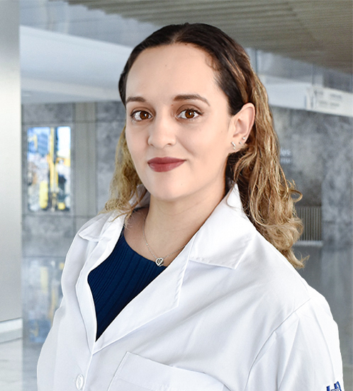 Es la foto de perfil de una ginecóloga y obstetra en Querétaro de Hospital Angeles Centro-sur. Usa una bata blanca con una blusa azul oscuro. Tiene el cabello rubio, chino y corto. Usa un collar color plata.