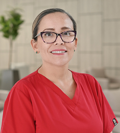 Es la foto de perfil de una anestesióloga en Querétaro de Hospital Angeles Centro Sur. Usa un uniforme rojo, tiene lentes cuadrados y aretes verde.