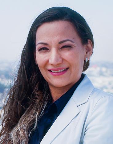 Es la foto de perfil de una otorrinolaringóloga en Torreón de Hospital Angeles Torreón. Usa una bata blanca y una camisa negra. Tiene el cabello largo, negro y ondulado. Está sonriendo.