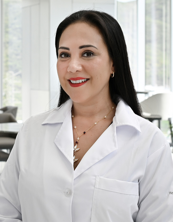 Es la foto de perfil de una hematóloga pediátrica en San Pedro Garza de Hospital Angeles Valle Oriente. Usa una blusa blanca. Tiene el cabello negro y lacio. Está sonriendo.