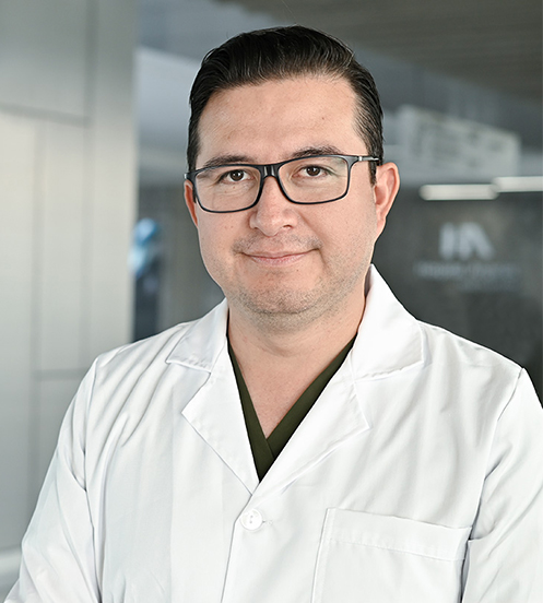 Es la foto de perfil de un urólogo en Querétaro de Hospital Angeles Centro Sur. Usa una camisa blanca con lineas azules y tiene cabello oscuro.