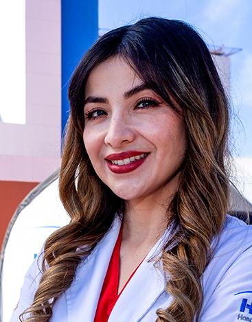 Es la foto de perfil de un otorrinolaringólogo en Tijuana de Hospital Angeles Tijuna. Usa una bata blanca con una blusa roja. Tiene el cabello largo, café y ondulado. Está sonriendo. Usa un labial rojo.