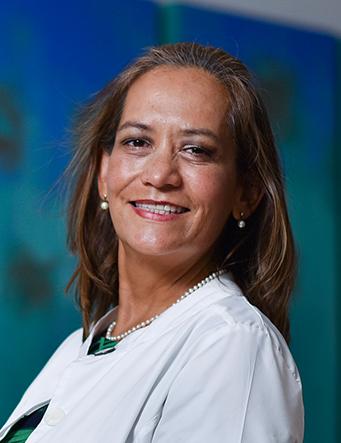 Es la foto de perfil de una audióloga y foniatra en Villahermosa de Hospital Angeles. Usa una bata blanca. Tiene el cabello corto y café. Está de perfil y sonriendo.