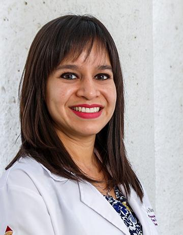 Es la foto de perfil de una otorrinolaringóloga en León de Hospital Angeles León. Utiliza una bata blanca con una blusa azul. Tiene el cabello castaño oscuro, está sonriendo y es de tez morena clara.