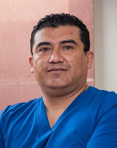 Es la foto de perfil de un ortopedista y traumatólogo en San Luis Potosí de Hospital Angeles. Usa un uniforme médico azul oscuro. Tiene el cabello negro y los brazos cruzados.