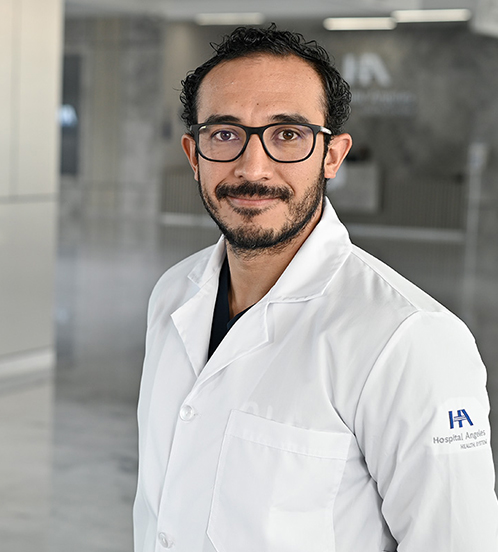 Es la foto de perfil de un urólogo en Querétaro de Hospital Angeles Centro Sur. Usa un uniforme negro, unos lentes cuadrados y un reloj.