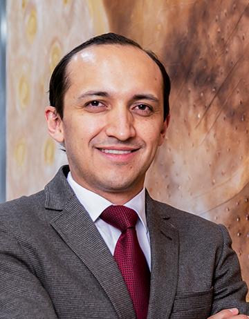 Es la foto de perfil de un urólogo en León de Hospital Angeles León. El doctor viste un traje gris con una camisa blanca y una corbata roja.