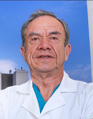 Es la foto de perfil de un ortopedista y traumatólogo en Ciudad de México de Hospital Angeles Clínica Londres. Utiliza una bata blanca con un uniforme azul debajo y su cabello es canoso.