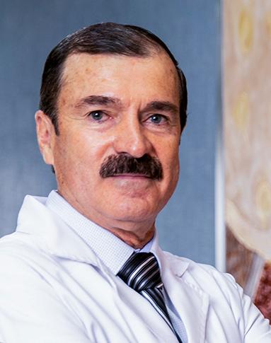 Es la foto de perfil de un odontólogo en León de Hospital Angeles León. Usa una bata blanca, camisa y una corbata, tiene el cabello negro y bigote.