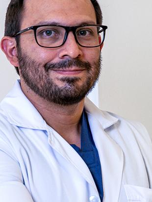 Es la foto de perfil de un especialista en medicina de rehabilitación en León de Hospital Angeles León. Utiliza una bata blanca, tiene barba, lentes y está sonriendo.