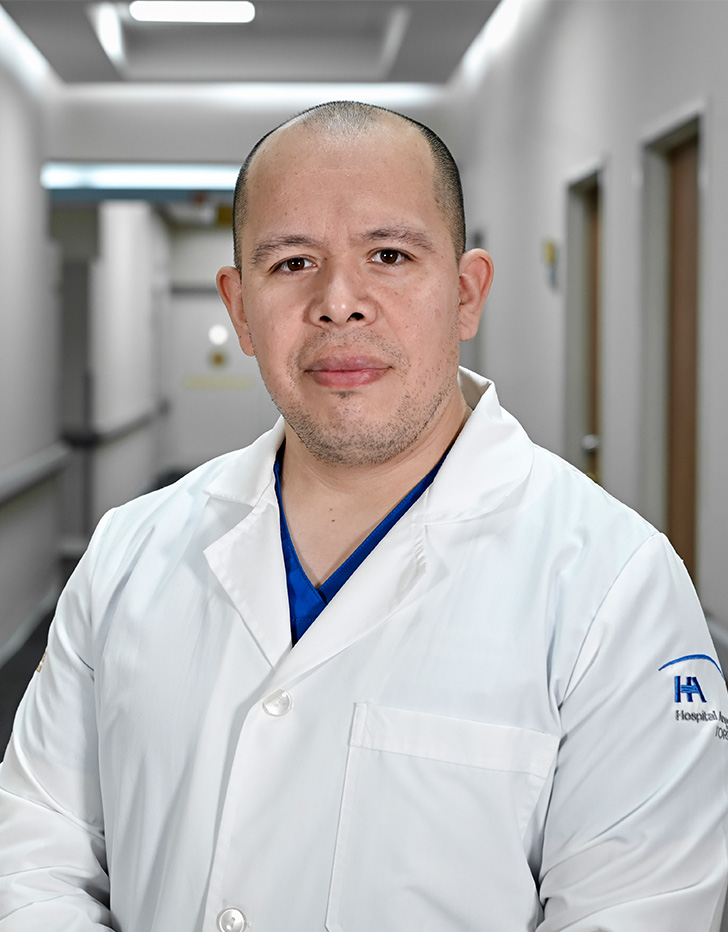 Es la foto de perfil de un cardiólogo intervencionista y cardiólogo en Torreón de Hospital Angeles. Usa un uniforme médico azul. Tiene parte de su cabello gris. Usa lentes. Está serio.