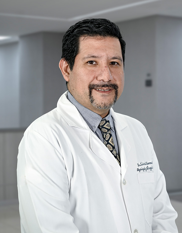 Es la foto de perfil de un angiólogo y cirujano vascular y endovascular en Ciudad de México de Hospital Angeles Lindavista. Tiene el cabello negro. está sonriendo. Usa una bata blanca y un uniforme médico negro.