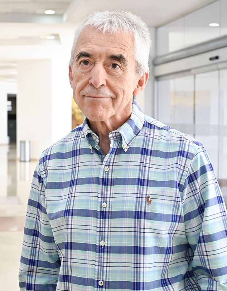 Es la foto de perfil de un dermatólogo en Ciudad Juárez de Hospital Angeles Ciudad Juárez. Utiliza una camisa blanca con lineas moradas y azul cielo en diferentes tamaños y tonos.