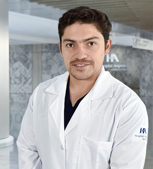 Es la foto de perfil de un cirujano general en Querétaro de Hospital Angeles Centro-sur. Usa una bata blanca con un uniforme médico color azul oscuro. Tiene el cabello ondulado y café.