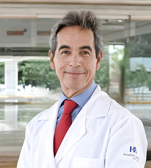 Es la foto de perfil de un ginecólogo y obstetra en Culiacán de Hospital Angeles Culiacán. Utiliza un uniforme médico azul con un playera azul marino debajo, usa lentes y tiene el cabello canoso.