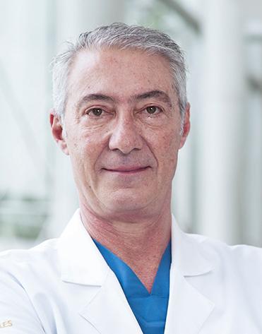 Es la foto de perfil de un ginecólogo y obstetra en Huixquilucan de Hospital Angeles Lomas. Usa una bata blanca, una playera azul y tiene el cabello canoso.