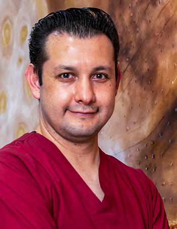 Es la foto de perfil de un pediatra en León de Hospital Angeles León. Utiliza un uniforme rojo con cuello V.