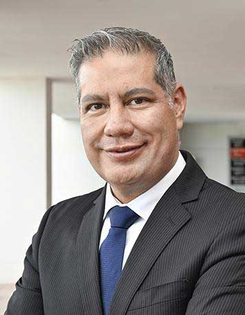 Es la foto de perfil de un urólogo en León de Hospital Angeles León. Utiliza un saco negro con una camisa y una corbata azul marino.