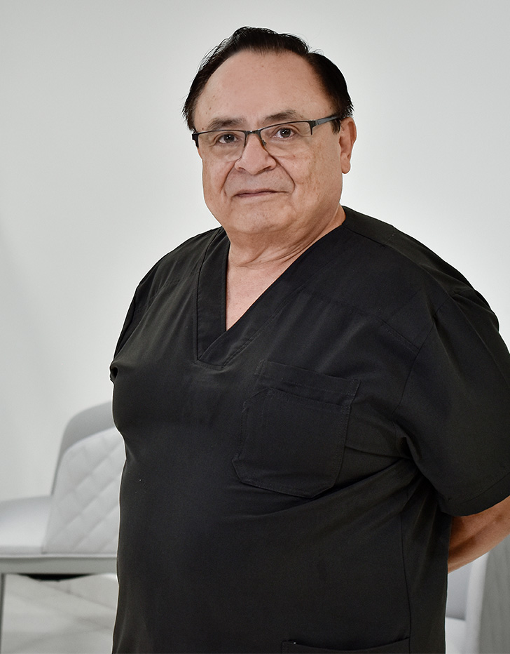 Es la foto de perfil de un artroscopista, ortopedista y traumatólogo en Ciudad de México de Hospital Angeles Clínica Londres. Utiliza un uniforme negro, es de tez morena y de fondo se ve el hospital. 