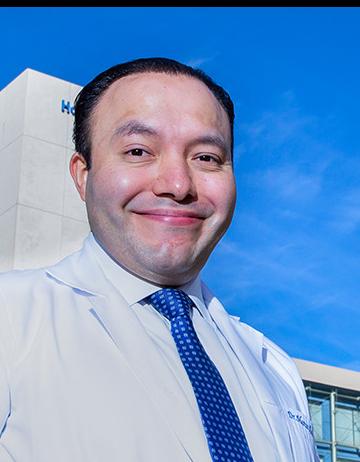 Es la foto de perfil de un ginecólogo en Huixquilucan de Hospital Angeles Lomas. Usa una bata blanca con camisa blanca y corbata azul. 