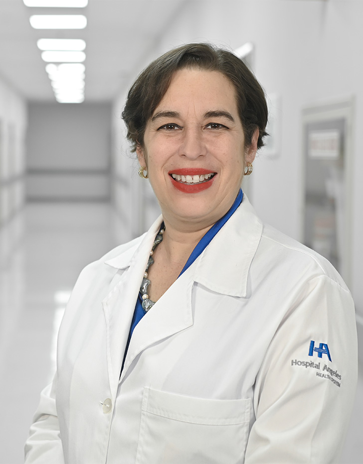 Es la foto de perfil de una otorrinolaringóloga en Ciudad de México de Hospital Angeles Universidad. Usa una bata blanca con una blusa azul. Tiene el cabello café oscuro. Usa un labial rojo. Está sonriendo.