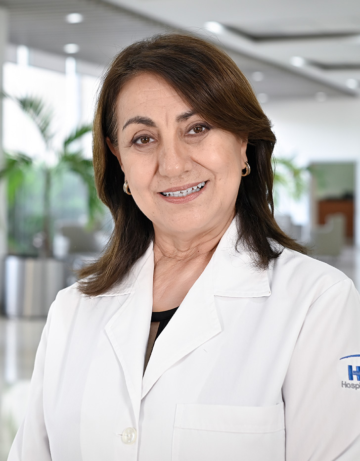 Es la foto de perfil de una ginecóloga en Tampico de Hospital Angeles. Usa una bata blanca con una blusa amarilla. Tiene el cabello café. Usa aretes plateados. Está sonriendo ligeramente.