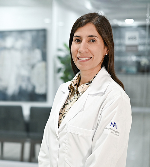 Es la foto de perfil de una reumatóloga en Ciudad de México de Hospital Angeles Acoxpa. Usa una bata blanca con una blusa café con negro.Tiene el cabello largo y castaño. Está sonriendo.