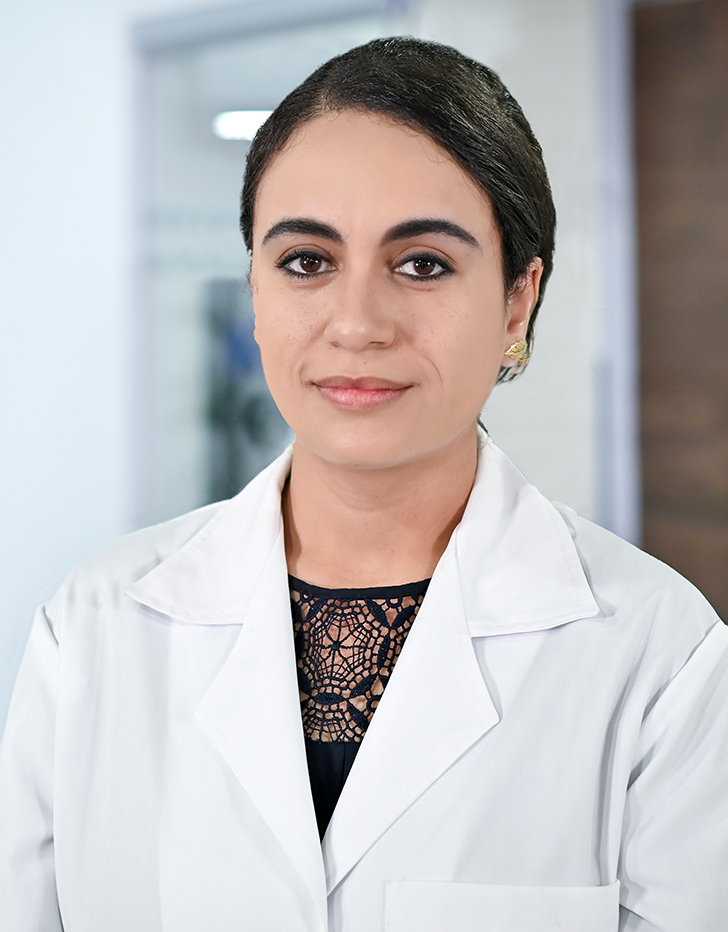 Es la foto de perfil de una ginecóloga en Ciudad de México de Hospital Angeles Santa Mónica. Usa una bata blanca con una blusa negra. Tiene el cabello café y está recogido. Está sonriendo ligeramente.