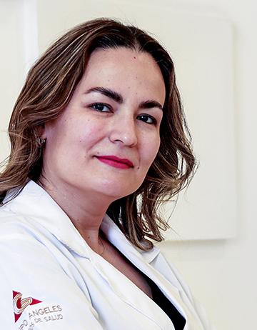 Es la foto de perfil de una cirujana general en León de Hospital Angeles León. Utiliza una bata blanca, blusa negra, tiene el cabello ondulado y con luces rubias.