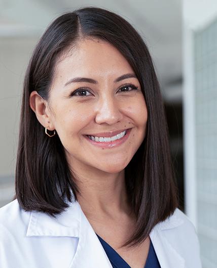 Es la foto de perfil de una dermatóloga pediátrica en Huixquilucan de Hospital Angeles Lomas. Usa una bata blanca con un uniforme azul marino debajo, tiene cabello corto negro.