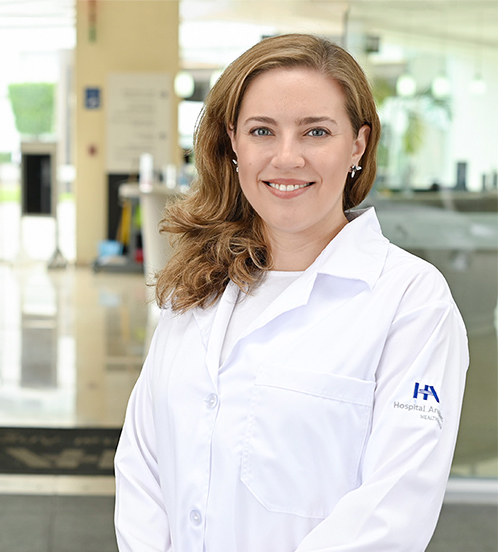 Es la foto de perfil de una genetista en Ciudad de México de Hospital Angeles Acoxpa. Usa una bata y blusa blanca. Tiene el cabello corto, ondulado y rubio/castaño.