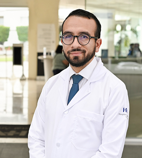 Es la foto de perfil de un cardiólogo en Ciudad de México de Hospital Angeles Acoxpa. Usa una bata y camisa blanca con una corbata azul. Usa lentes negros.