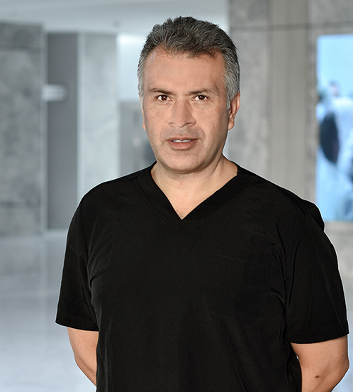 Es la foto de perfil de un cirujano plástico en Querétaro de Hospital Angeles Centro Sur. El doctor tiene un uniforme negro con cuello v y tienen las manos cruzadas por detrás.