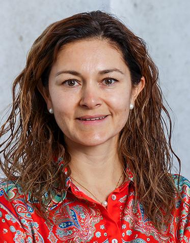 Es la foto de perfil de una dermatóloga en León de Hospital Angeles León. Utiliza una blusa roja, tiene el cabello castaño y ondulado y la doctora está sonriendo.