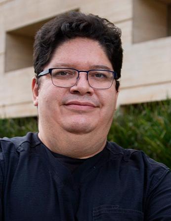 Es la foto de perfil de un urólogo en Ciudad de México de Hospital Angeles. Viste un uniforme negro, lentes y está sonriendo.