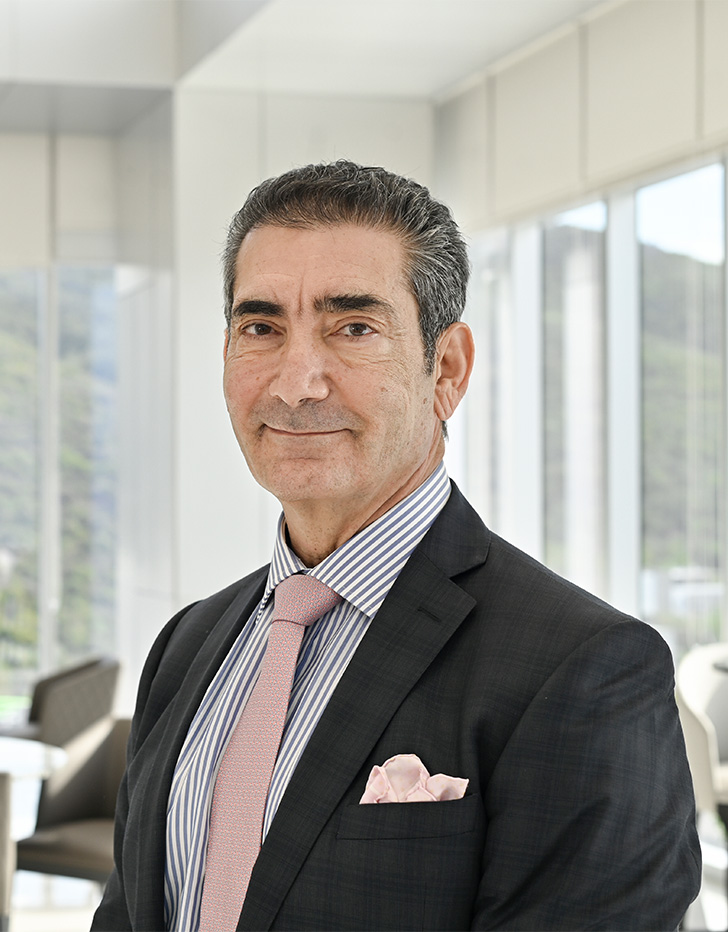 Es la foto de perfil de un cirujano plástico en San Pedro Garza de Hospital Angeles Valle Oriente. Usa un saco negro con una camisa azul y una corbata rosada. Tiene el cabello gris. Está sonriendo ligeramente.