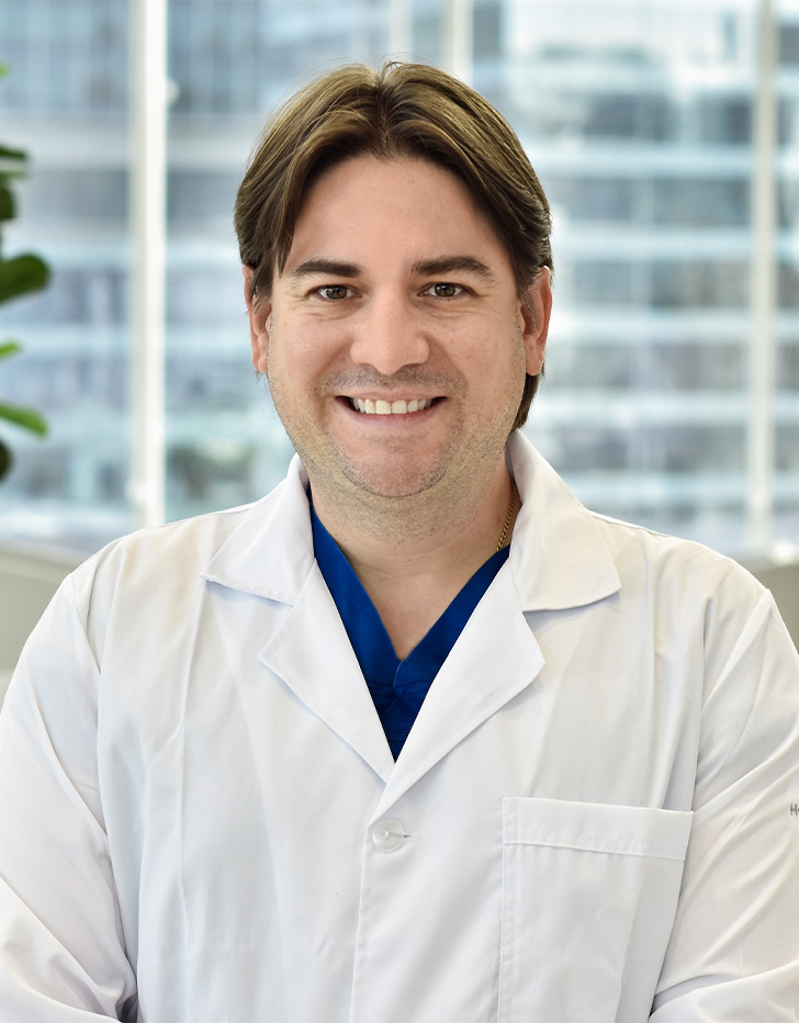 Es la foto de perfil de un geriatra en San Pedro Garza de Hospital Angeles Valle Oriente. Usa una bata blanca. Tiene el cabello castaño. Está sonriendo.