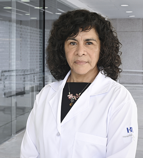 Es la foto de perfil de una otorrinolaringóloga en Villahermosa de Hospital Angeles. Usa una bata blanca con una blusa vino. Tiene el cabello corto y chino, color negro. Está de perfil.